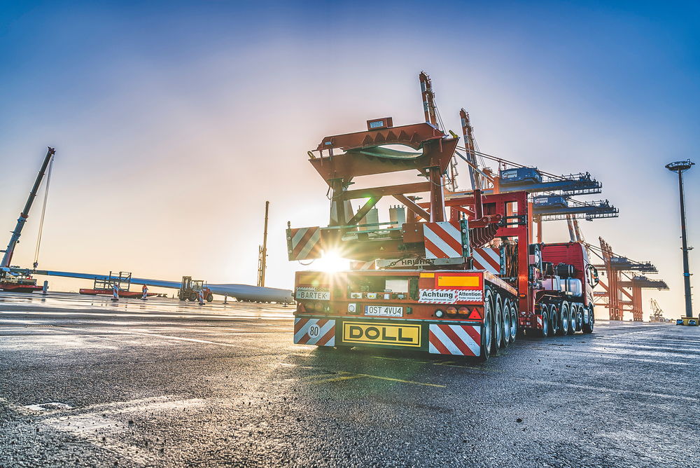 Schwertransportfahrzeug von DOLL für Windkraftanlagen am Hafen bei Sonnenaufgang