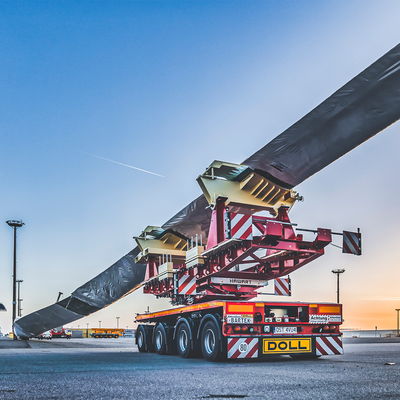 Schwertransportfahrzeug von DOLL für Windkraftanlagen am Hafen bei Sonnenuntergang