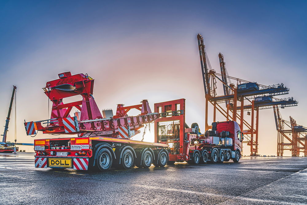 Schwertransportfahrzeug von DOLL für Windkraftanlagen am Hafen bei Sonnenuntergang