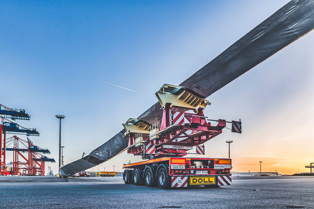 Schwertransportfahrzeug von DOLL für Windkraftanlagen am Hafen bei Sonnenuntergang